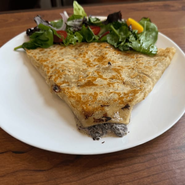 Savory crepe with a side salad on a white plate at Cafe Miriam.