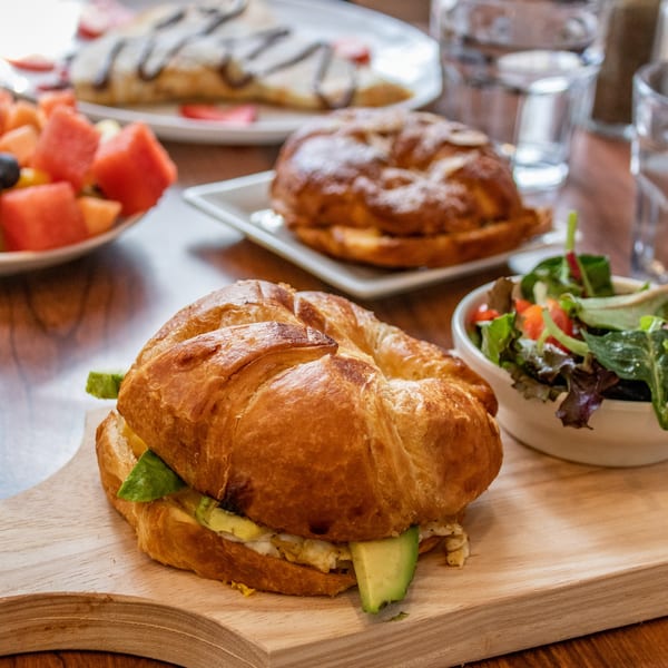 Cafe Miriam's croissant sandwich with avocado and egg, served with a side salad.