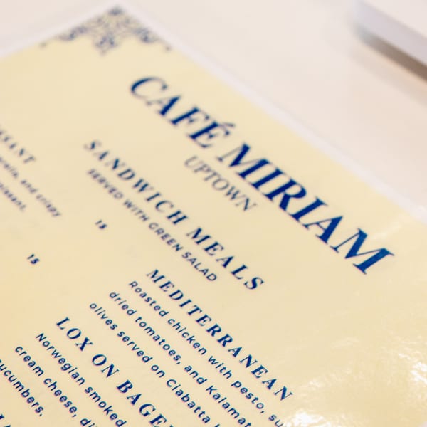 A close-up of the Cafe Miriam menu, featuring sandwich meals and breakfast options.